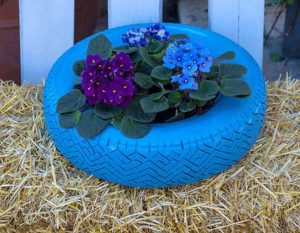 Pot de fleurs à rebord peint en bleu et avec des fleurs colorées