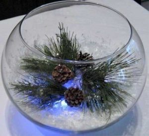 Bol en verre avec branches de pin, pommes de pin et neige artificielle