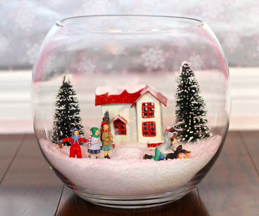 Bol en verre avec neige artificielle, pins, petite maison et autres figurines