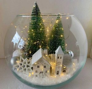 Bol en verre avec pins, maison, flocons de neige, boules et lumières